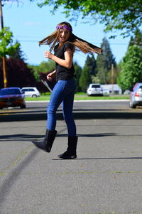 Full length of teenage girl tossing hair while standing on road