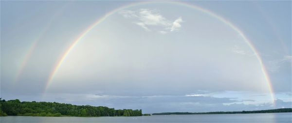 Scenic view of rainbow over sea against sky