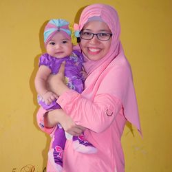 Portrait of smiling woman standing against yellow wall