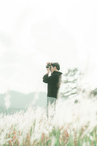 Man photographing on field against sky