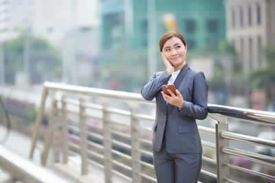 Full length of woman standing by railing in city