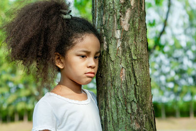 Portrait of cute girl with tree trunk