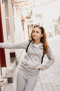 Portrait of girl standing on street by built structure