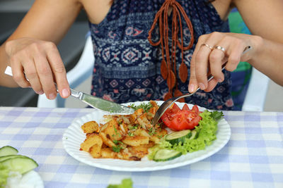 Midsection of woman eating food at table