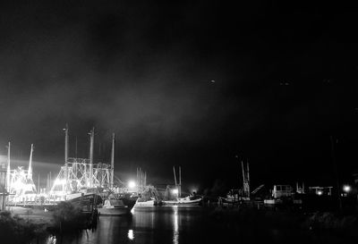Sailboats moored at harbor against sky at night