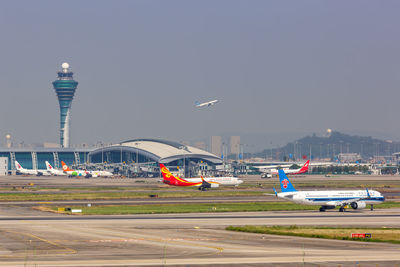 Airplane flying over airport in city against sky