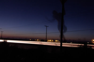 Illuminated street against sky at night