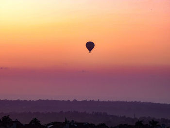 Silhouette hot air balloon flying in sky during sunset