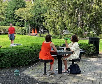 People sitting on seat against trees