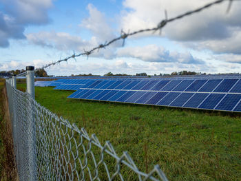 View over metal fence of solar panels on field in germany