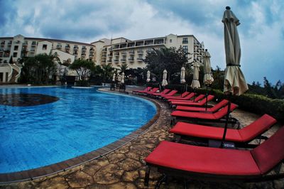 Chairs by swimming pool against buildings in city