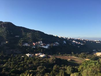 High angle view of townscape and mountains against clear blue sky