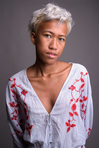 Portrait of young woman standing against black background