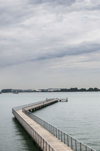 Pier on sea against cloudy sky