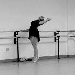 Full length of ballerina practicing at dance studio