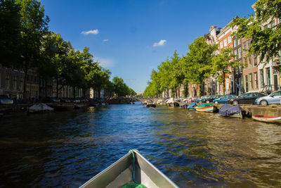 Boats moored on river in city against blue sky