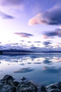 Scenic view of lake pukaki by snowcapped mountains against cloudy sky