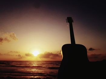 Silhouette of man on beach against sky during sunset