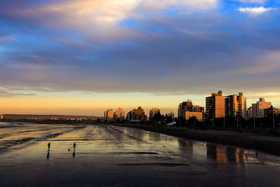 Scenic view of river and buildings against sky during sunset