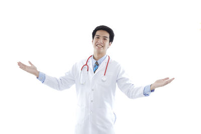 Portrait of smiling young man standing against white background