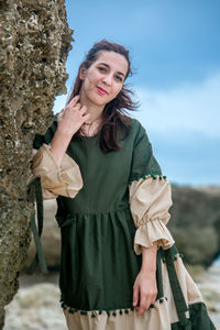 Portrait of young woman standing against sky