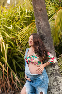 Pregnant young woman standing by tree in park