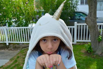 Portrait of cute girl wearing gesturing while wearing unicorn costume in yard 