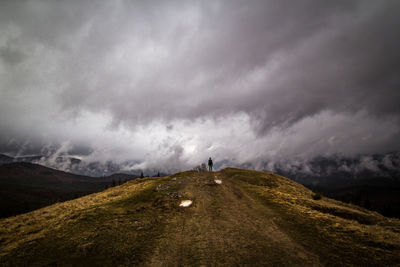 Hiker standing on dry grass hill landscape photo