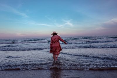 Rear view of man standing on beach against sky