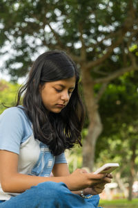 Young woman looking away while sitting outdoors