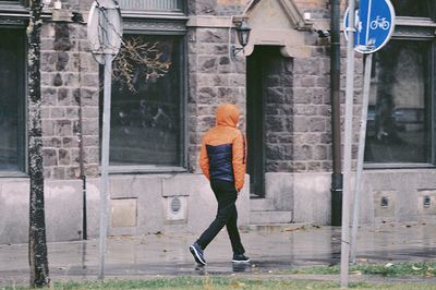 Full length side view of woman standing against building