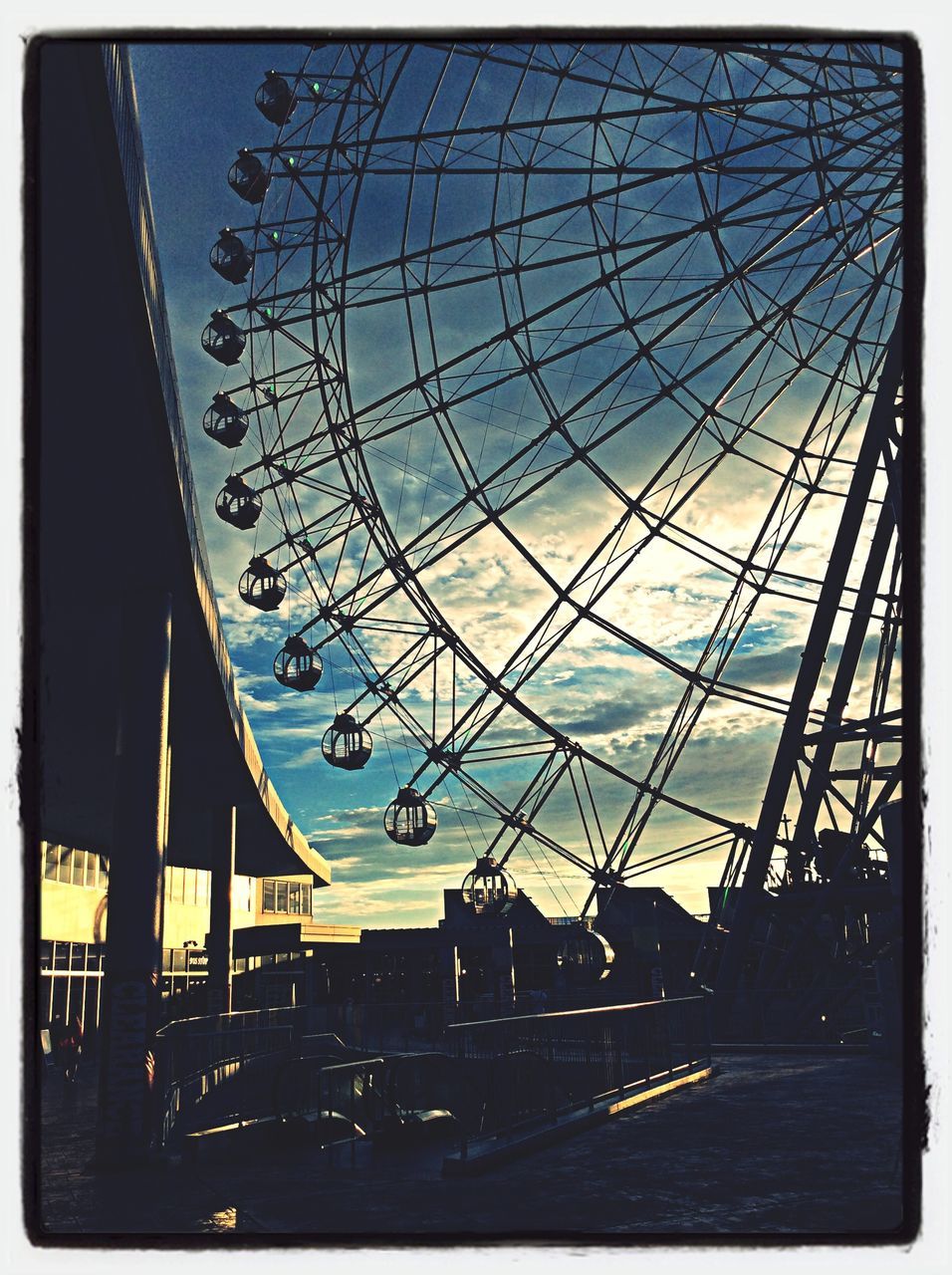 transfer print, built structure, architecture, auto post production filter, sky, ferris wheel, amusement park, transportation, arts culture and entertainment, amusement park ride, silhouette, city, building exterior, mode of transport, low angle view, dusk, outdoors, incidental people, travel, bridge - man made structure