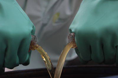 Midsection of scientist pouring liquid