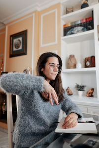 Full length portrait of woman sitting at home