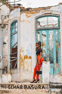 Full length portrait of woman sitting in abandoned building