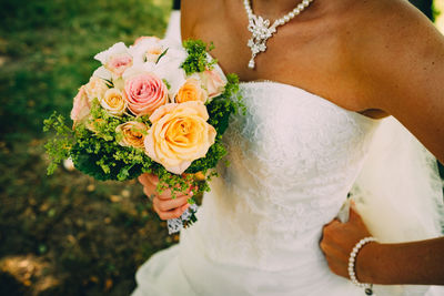 Midsection of bride holding rose bouquet