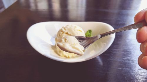 Cropped hand of person holding spoon with ice cream