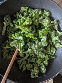 A wok full of fresh kale, viewed from above