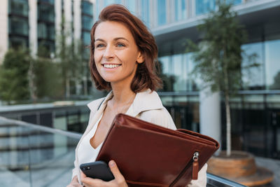 Portrait of young woman using mobile phone in city