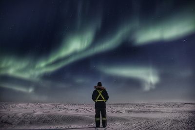Man looking at northern light while standing on snowcapped landscape