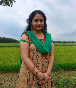 Portrait of beautiful young woman standing on agricultural field