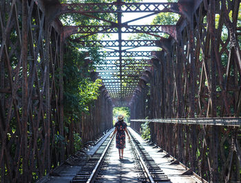 Rear view of man walking on footbridge