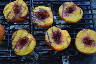 Peach halves grilling on top of a small tabletop hibachi grill on picnic table outdoors