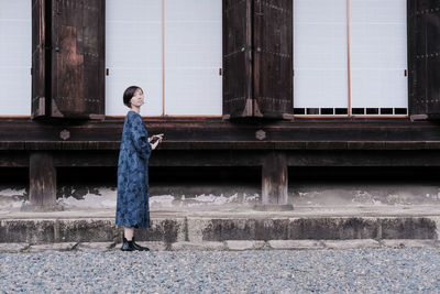 Full length of woman wearing dress while standing against building