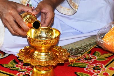 Midsection of priest pouring oil in diya during ceremony