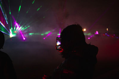 Girl catching light show on cellphone 