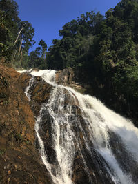 Scenic view of waterfall in forest against clear sky