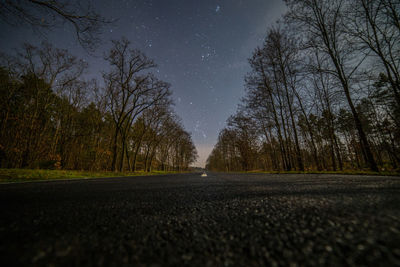 Diminishing road amidst trees at dusk