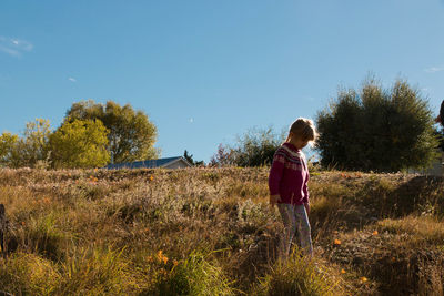 Girl standing on field against sky