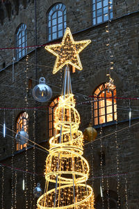 Low angle view of illuminated christmas tree against building